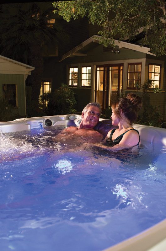 Couple relaxing in a Caldera hot tub on a warm evening