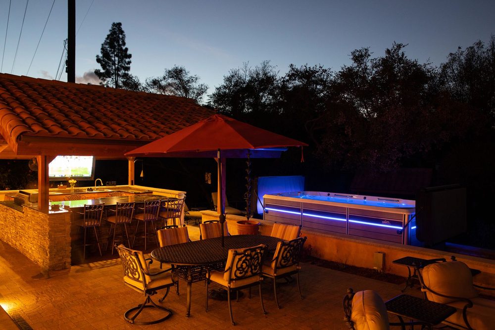 Endless Pools swim spa lit at dusk beside a covered patio