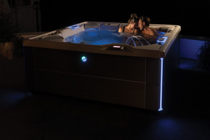 Hot Spring hot tub glowing on a backyard patio in the evening